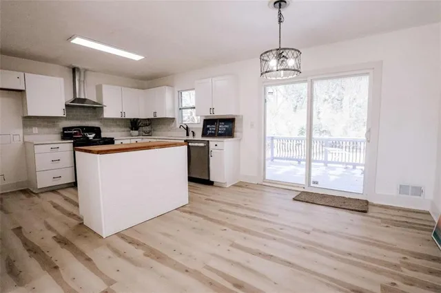 a kitchen with stainless steel appliances a dining table chairs stove refrigerator and sink