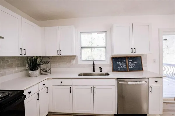 an empty room with wooden floor cabinet and windows