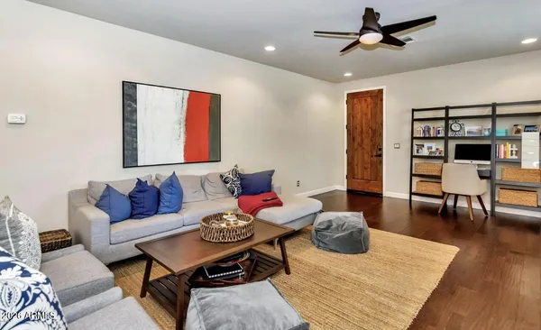 a living room with furniture kitchen view and a wooden floor