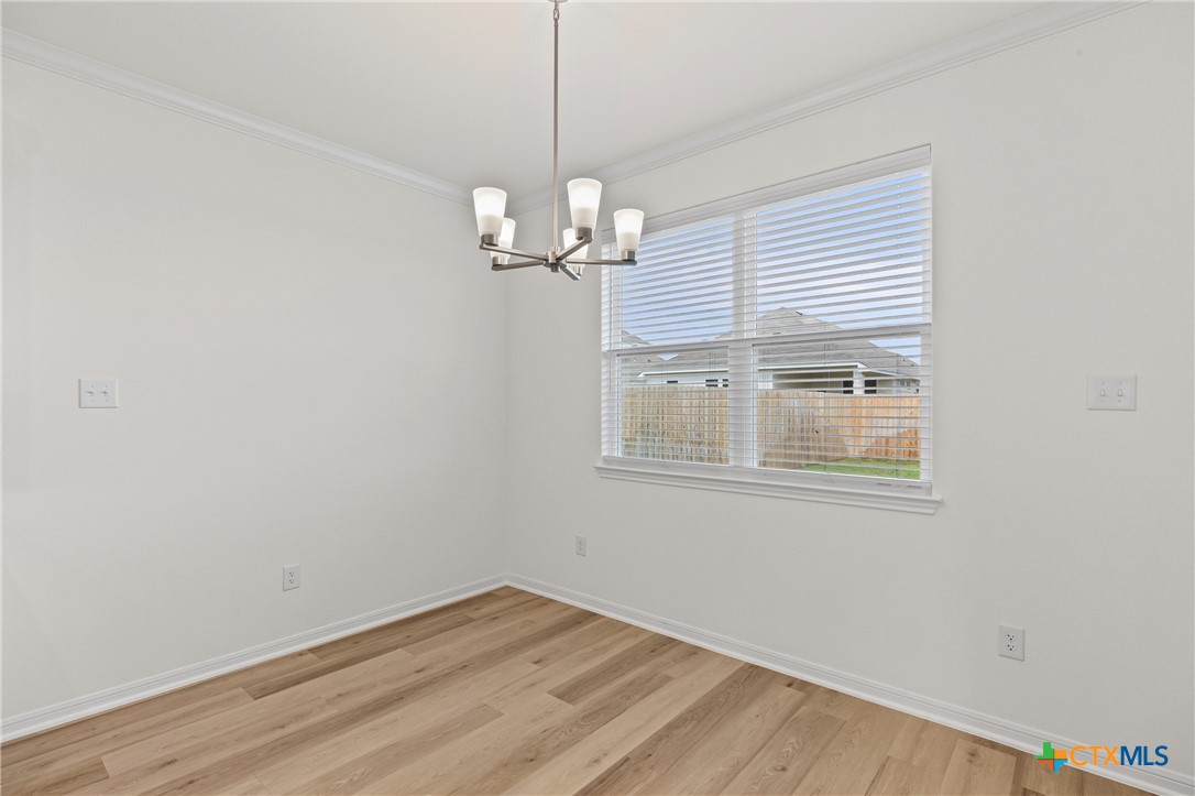 7806 Timber Holw Lane Temple, TX 76502 - Photo 13 of 30 an empty room with wooden floor chandelier and windows