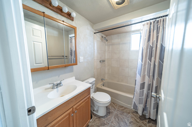 331 North 4th East Price, UT 84501 - Photo 7 of 7 Bathroom featuring a wood-finish vanity with an integrated sink, a mirrored medicine cabinet, a full bathtub with tile surround, and patterned flooring