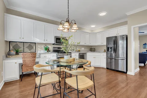 a kitchen with stainless steel appliances a dining table chairs stove refrigerator and cabinets