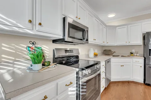 a kitchen with stainless steel appliances white cabinets and a stove top oven