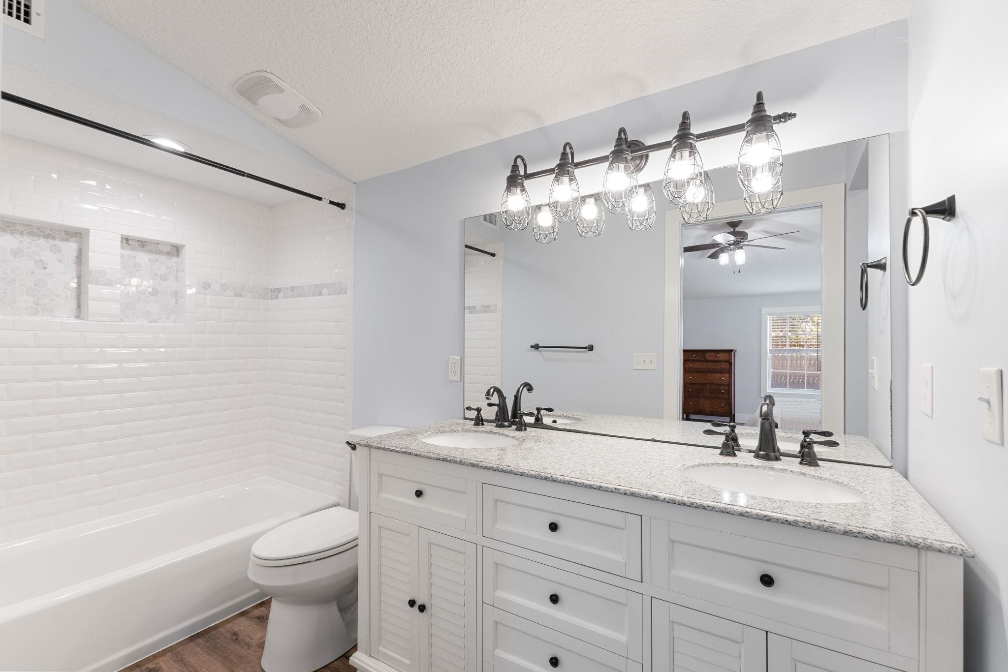 1385 Highland Boulevard St. Augustine, FL 32084 - Photo 20 of 47 a bathroom with a granite countertop double vanity sink toilet mirror and bathtub