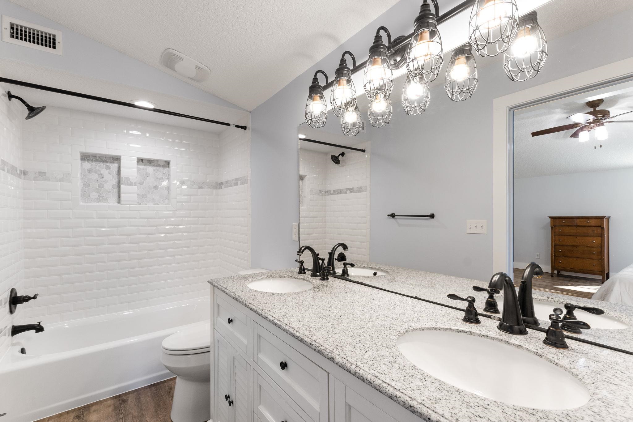 1385 Highland Boulevard St. Augustine, FL 32084 - Photo 21 of 47 a bathroom with a granite countertop sink a toilet a mirror a bathtub and shower