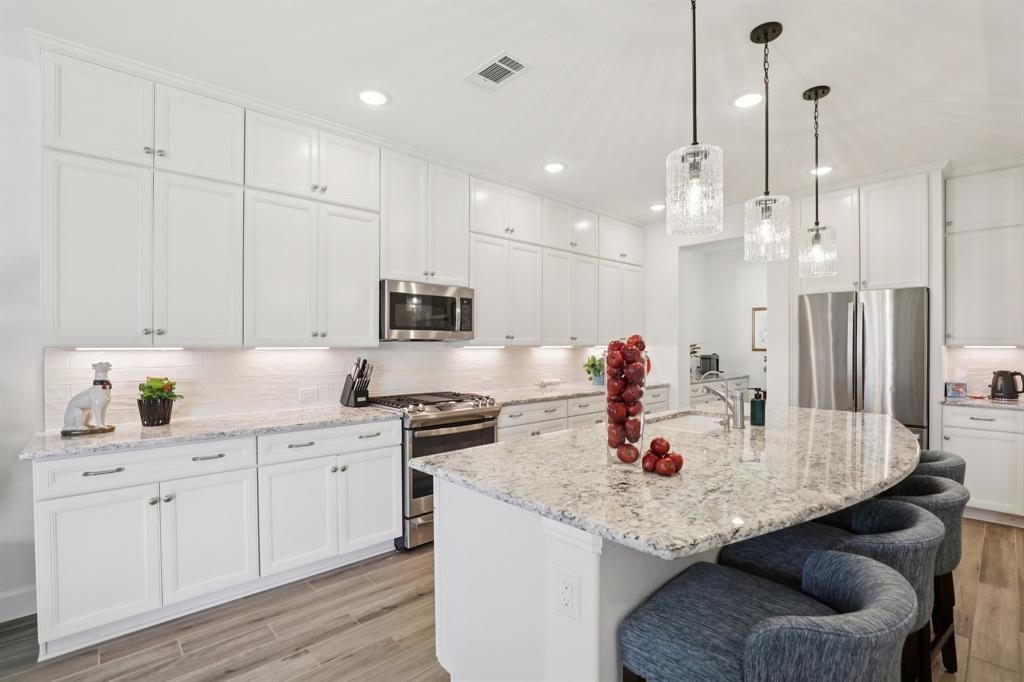 9716 Silver Rock Way Denton, TX 76207 - Photo 5 of 25 a kitchen with stainless steel appliances granite countertop a sink a stove and a wooden floors