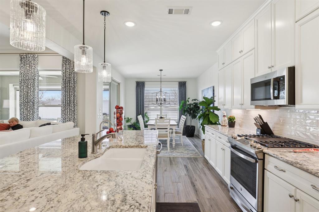 9716 Silver Rock Way Denton, TX 76207 - Photo 6 of 25 a kitchen with stainless steel appliances granite countertop sink stove and wooden floor