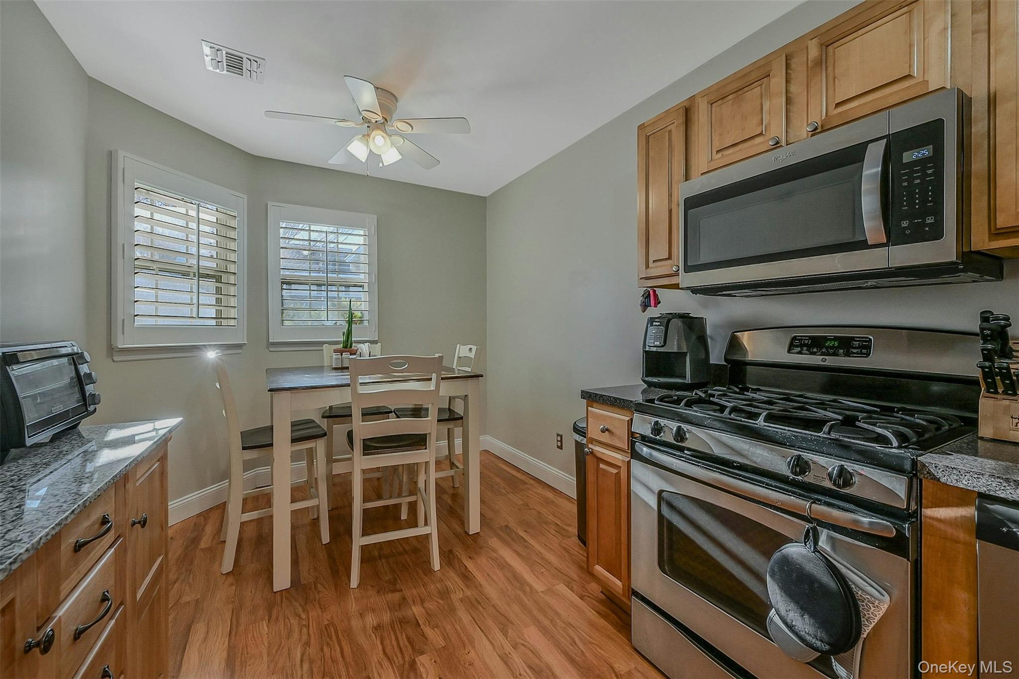50 Strawberry Commons Riverhead, NY 11901 - Photo 12 of 33 a kitchen with stainless steel appliances a stove a microwave and white cabinets