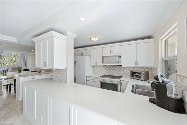 a kitchen with stainless steel appliances a stove a sink a refrigerator white cabinets and a refrigerator