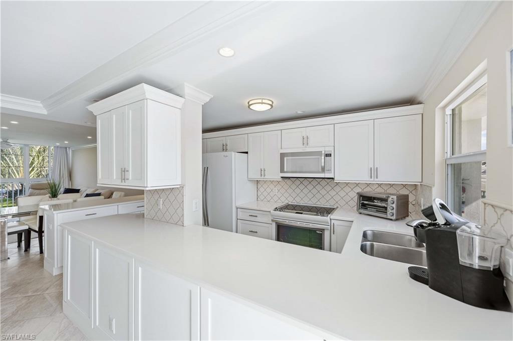 610 Broad Avenue South, Unit J610 Naples, FL 34102 - Photo 2 of 20 Kitchen with ornamental molding, white cabinetry, white appliances, recessed lighting, and decorative backsplash