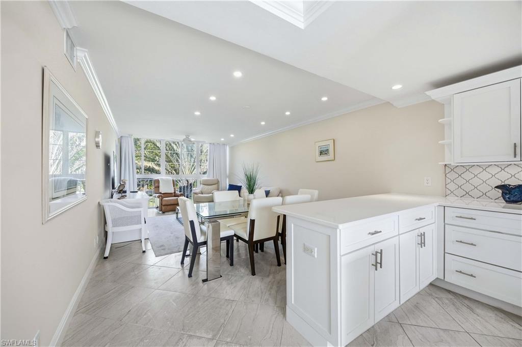 610 Broad Avenue South, Unit J610 Naples, FL 34102 - Photo 3 of 20 Kitchen with ornamental molding, open shelves, a peninsula, white cabinets, and decorative backsplash