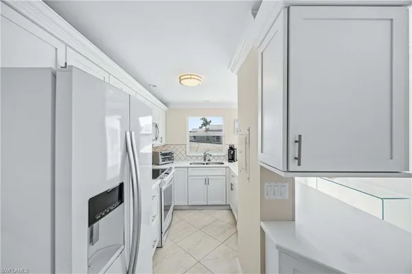 a kitchen with white cabinets and white appliances