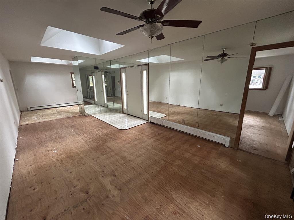 277 Prince Road Rocky Point, NY 11778 - Photo 6 of 19 Unfurnished room featuring a ceiling fan, a skylight, and baseboard heating