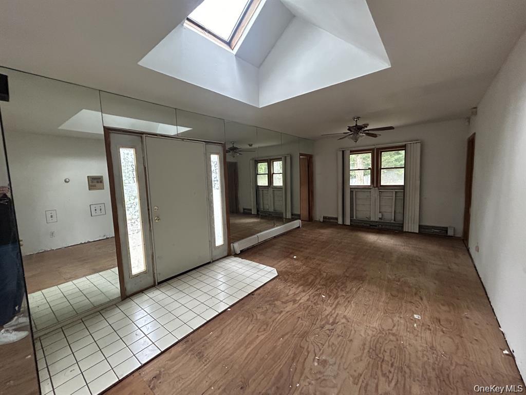 277 Prince Road Rocky Point, NY 11778 - Photo 10 of 19 Foyer with a skylight, a ceiling fan, wood finished floors, and vaulted ceiling