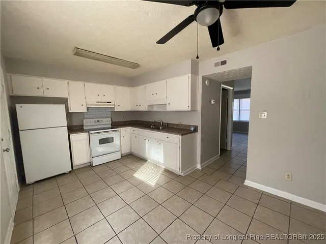 a kitchen with a refrigerator a stove top oven and cabinets