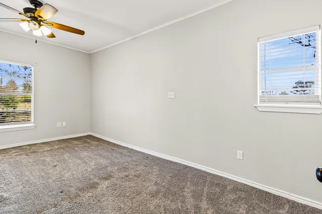 an empty room with windows and fan