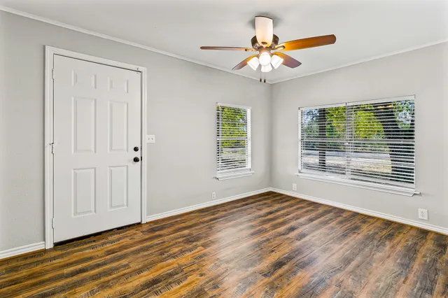 a view of an empty room with wooden floor and a window