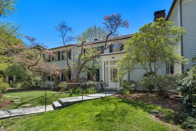 a view of a house with a big yard potted plants and large tree