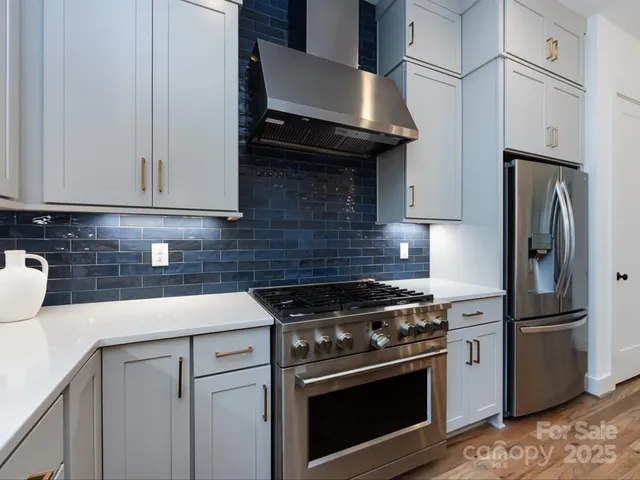 a kitchen with stainless steel appliances granite countertop a stove a refrigerator and a sink