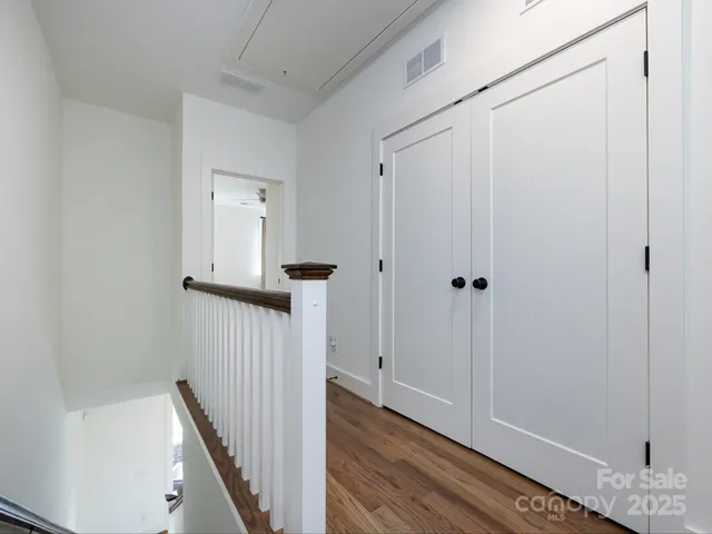 a view of a hallway with wooden floor and staircase