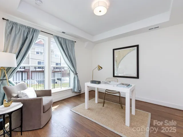 a living room with furniture a large window and wooden floor