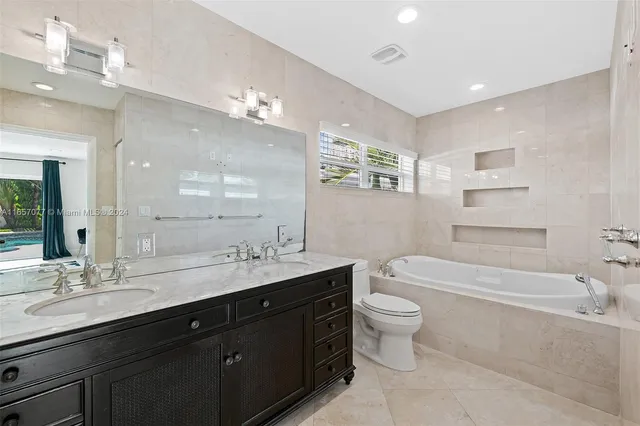 a bathroom with a double vanity sink toilet mirror and bathtub