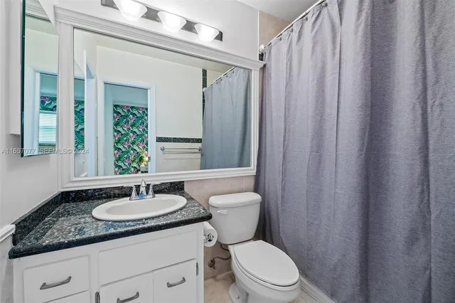 a bathroom with a granite countertop sink toilet and a mirror