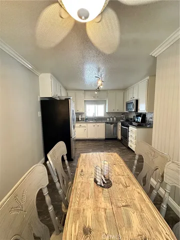 a kitchen with stainless steel appliances kitchen island granite countertop a refrigerator a sink a stove and white cabinets