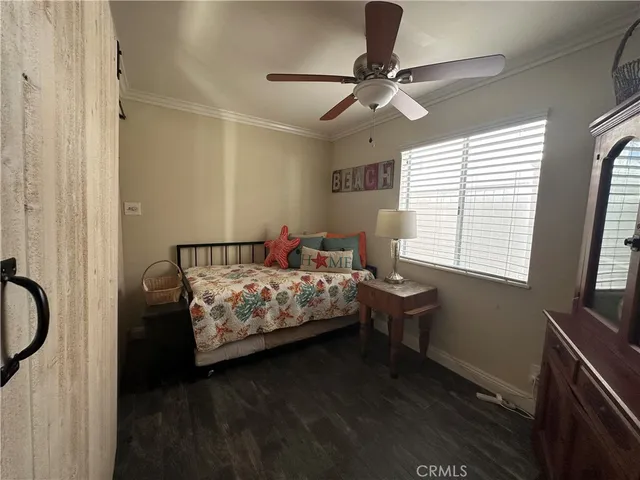 a bedroom with a bed table closet and two windows
