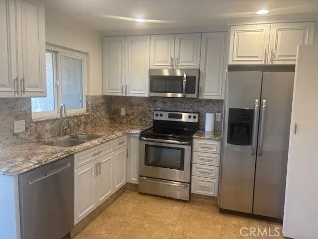 a kitchen with stainless steel appliances granite countertop a stove a sink and a refrigerator