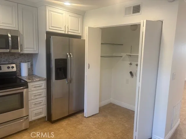 a view of kitchen with stainless steel appliances wooden floor and cabinet
