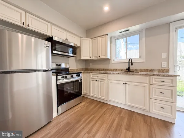 a kitchen with granite countertop stainless steel appliances a refrigerator sink and cabinets