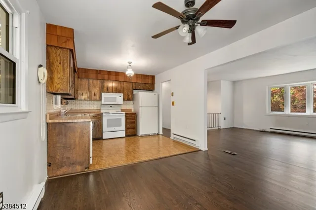a view of a kitchen with wooden floor a sink a refrigerator and window