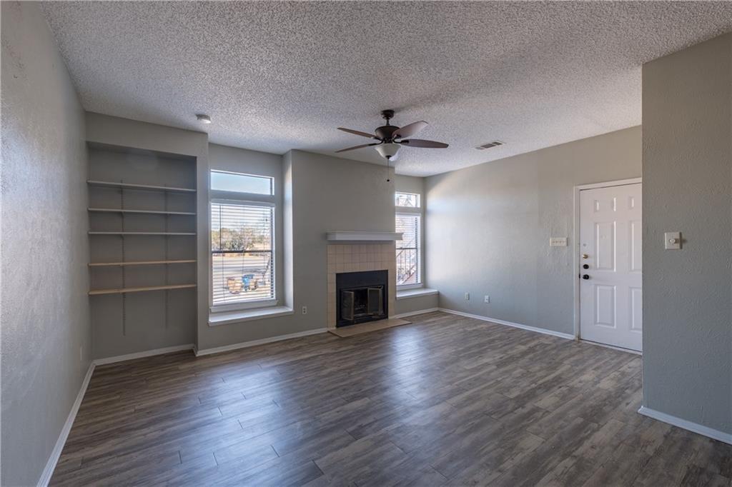 5305 Indio Cove, Unit B Austin, TX 78745 - Photo 10 of 19 an empty room with windows fireplace and a kitchen view