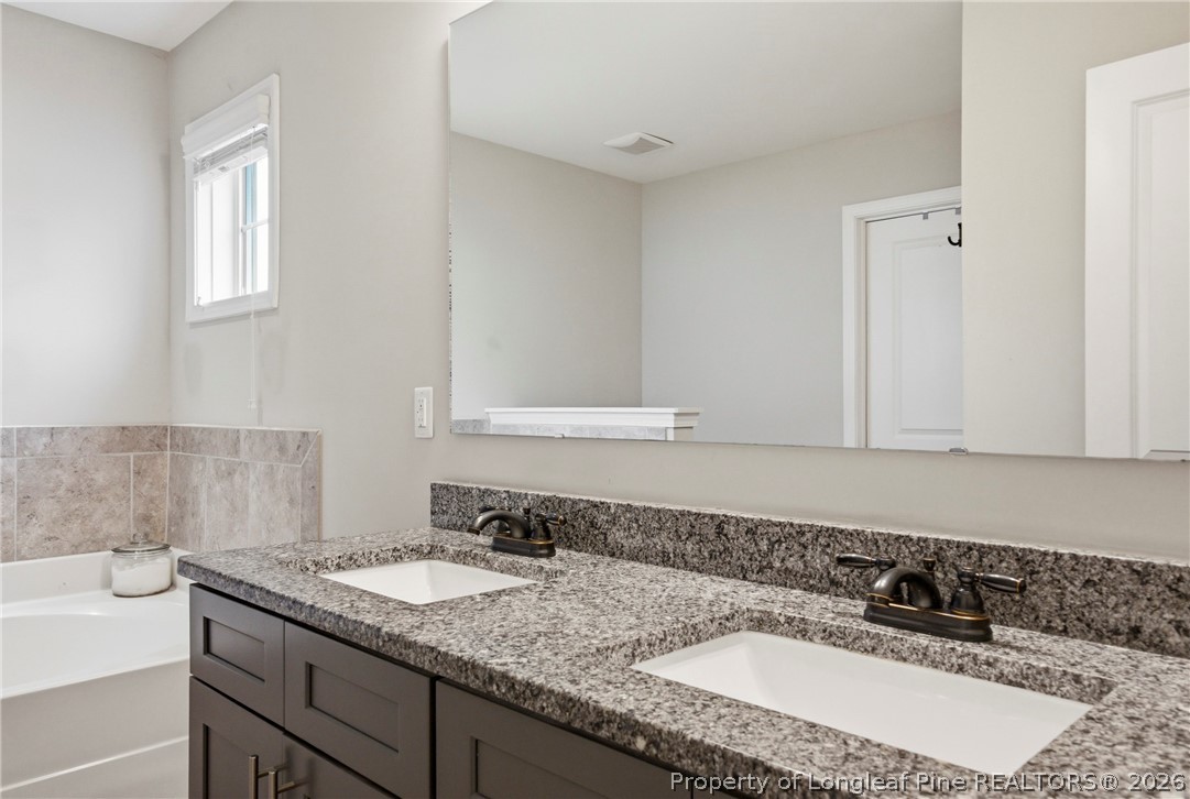 240 Meherrin Loop Raeford, NC 28376 - Photo 28 of 50 a bathroom with a granite countertop sink and a bathtub