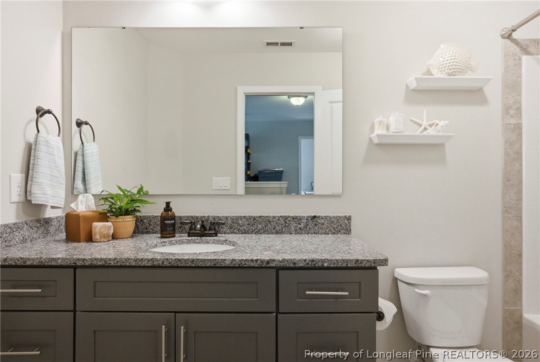 240 Meherrin Loop Raeford, NC 28376 - Photo 35 of 50 a bathroom with a granite countertop sink a toilet and mirror