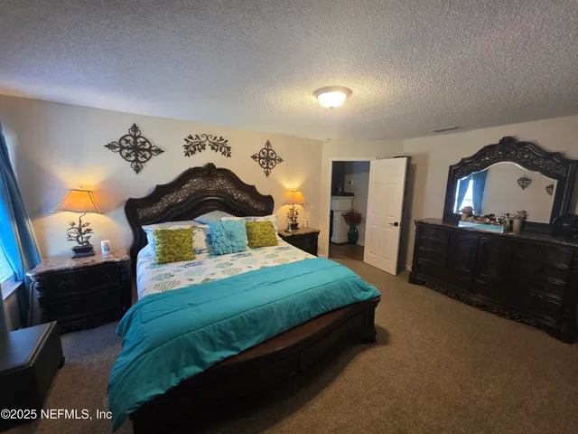 a spacious bedroom with a bed and a mirror on dresser
