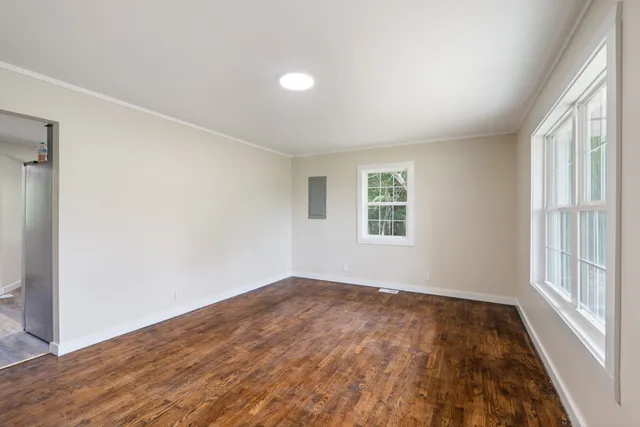 an empty room with wooden floor and windows