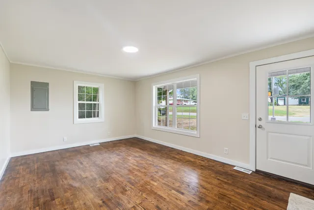 a view of an empty room with wooden floor and a window