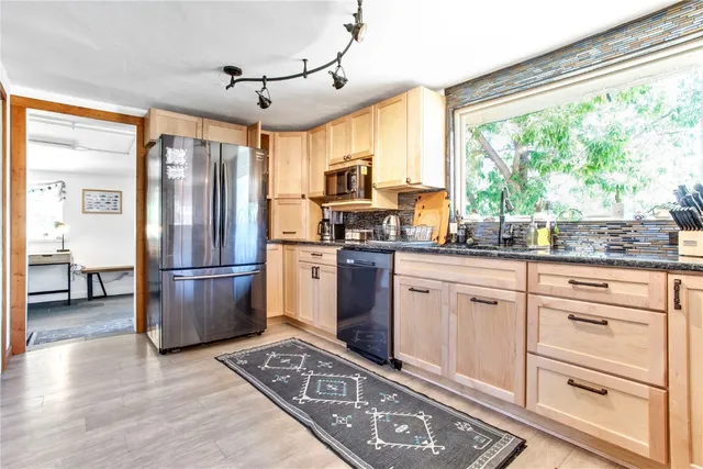 a kitchen with kitchen island granite countertop appliances cabinets and a large window