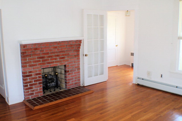 9593 Atlantic Road Atlantic, VA 23303 - Photo 7 of 20 an empty room with wooden floor fireplace and windows