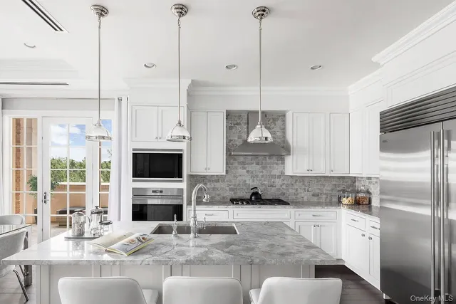 a kitchen with stainless steel appliances granite countertop a stove a kitchen island a refrigerator a stove a oven and white cabinets with wooden floor