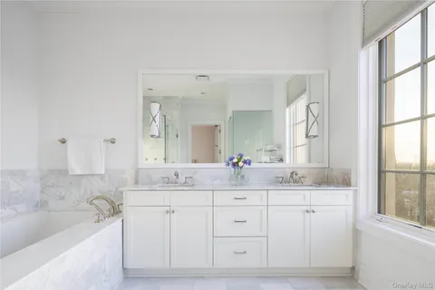 a bathroom with a double vanity sink a mirror and a bathtub