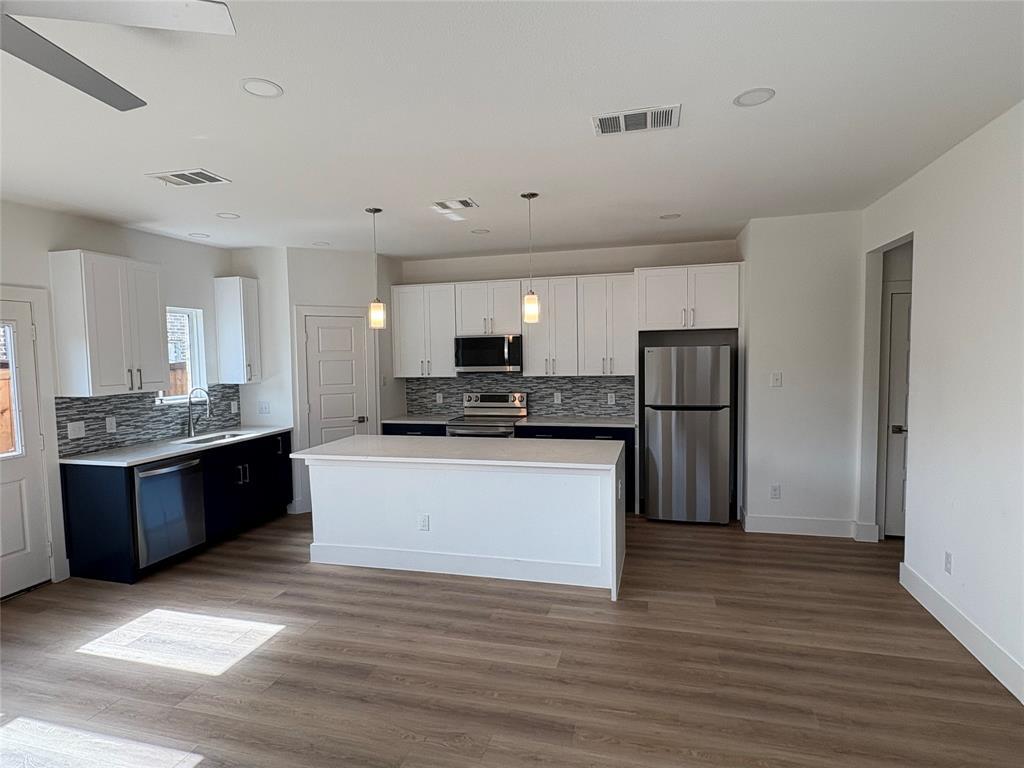 7307 Rubio Place Dallas, TX 75235 - Photo 7 of 17 a large white kitchen with stainless steel appliances granite countertop a stove a refrigerator a sink a oven and a refrigerator with wooden floor