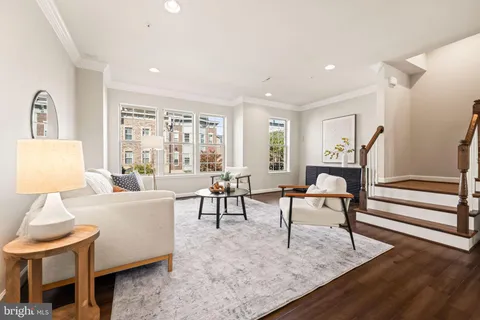 a work room with furniture a rug potted plant and a large window
