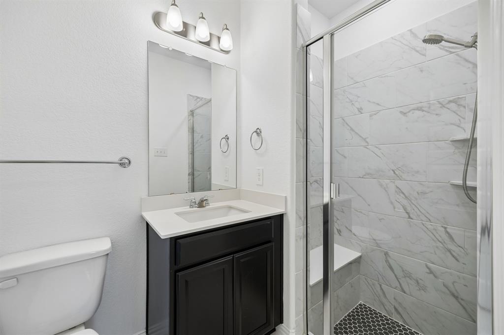 1303 Wheelwright Drive Forney, TX 75126 - Photo 26 of 39 1st floor guest Bathroom featuring a dark wood-finish vanity with a light countertop, a rectangular mirror, and an overhead light fixture