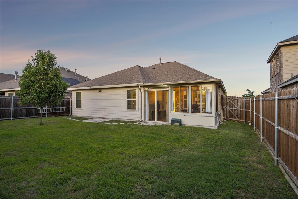 406 Madrone Lane Princeton, TX 75407 - Photo 25 of 30 Expansive backyard featuring a manicured lawn, a young tree, a privacy fence, and a sunroom with large windows and sliding glass doors