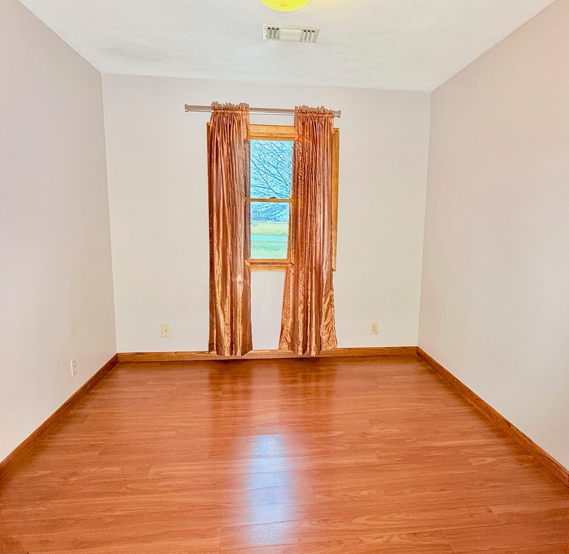 101 East 10th Street Gridley, IL 61744 - Photo 10 of 17 a view of an empty room with wooden floor and a window