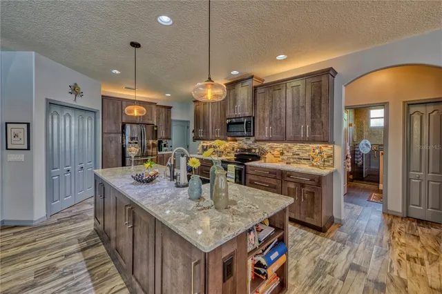 a kitchen with stainless steel appliances granite countertop sink stove top oven and refrigerator