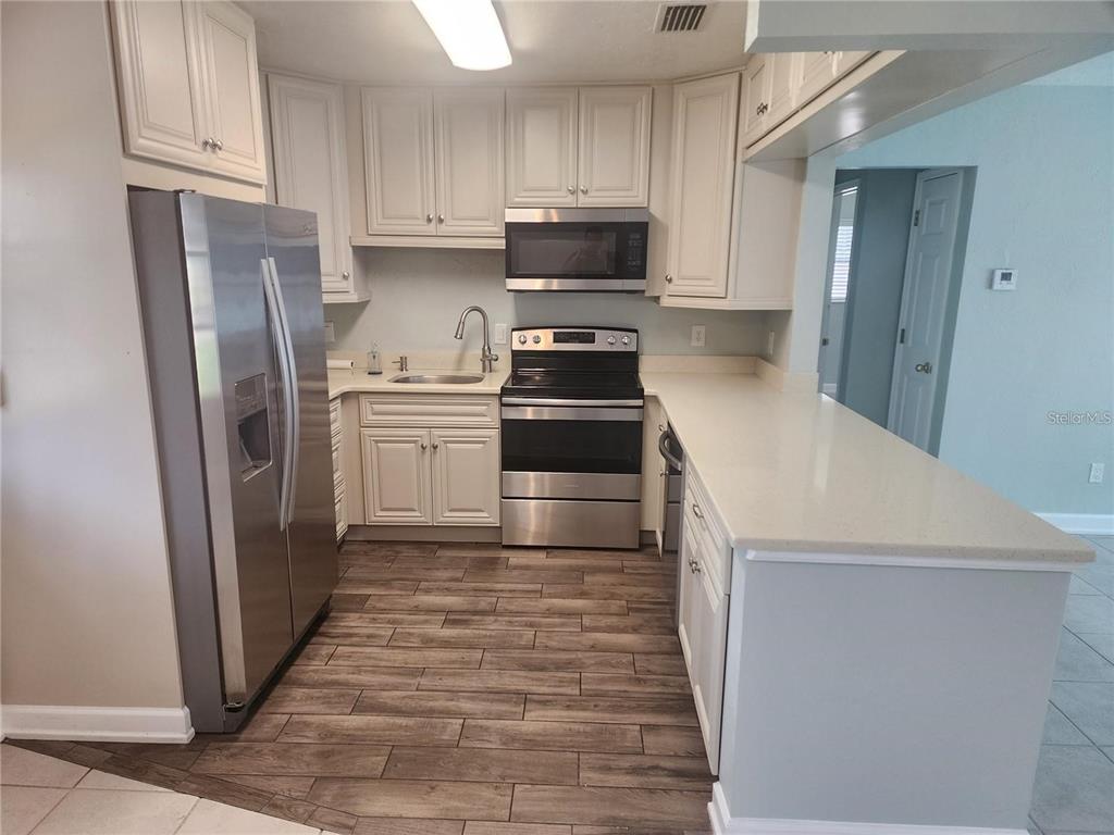 109 21st Street Northeast Bradenton, FL 34208 - Photo 12 of 14 a kitchen with granite countertop a refrigerator and a stove top oven